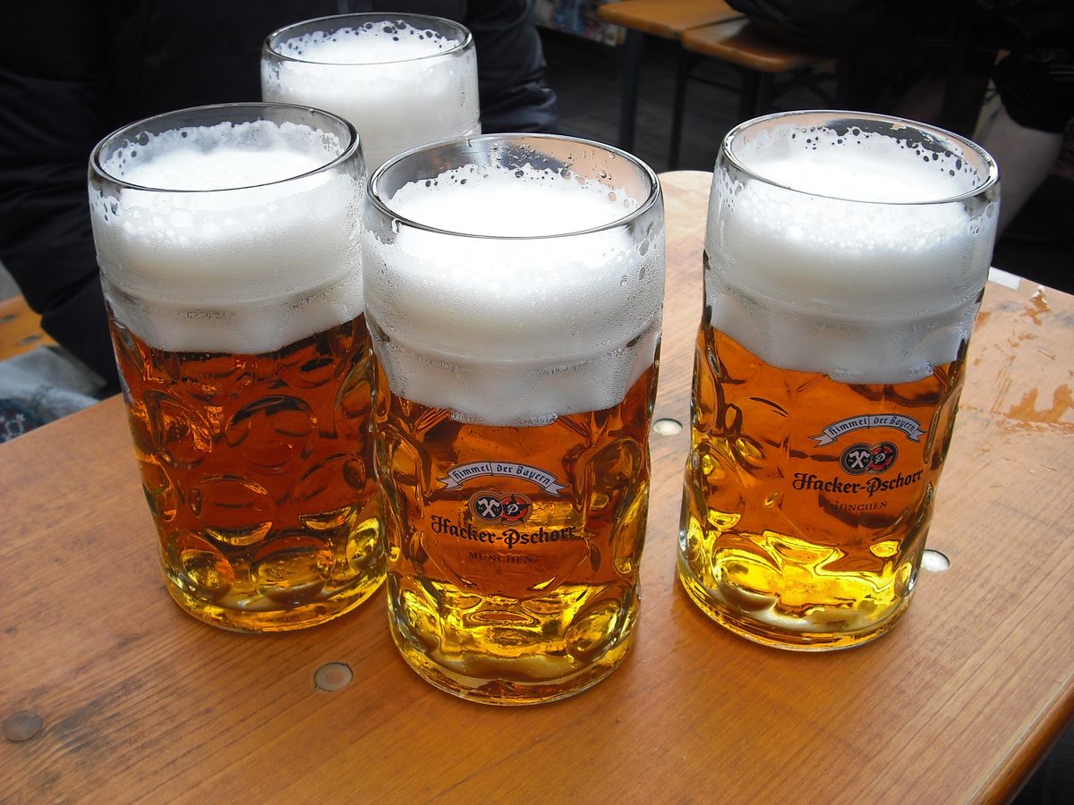 Four full beer mugs on a wooden table at Oktoberfest