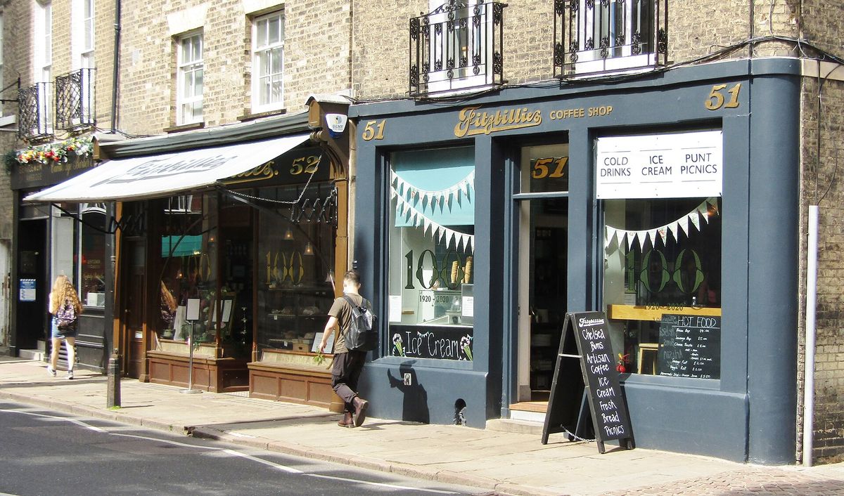 The blue shopfront of Fitzbillies on Trumpington Street with a chalkboard advertising Chelsea buns