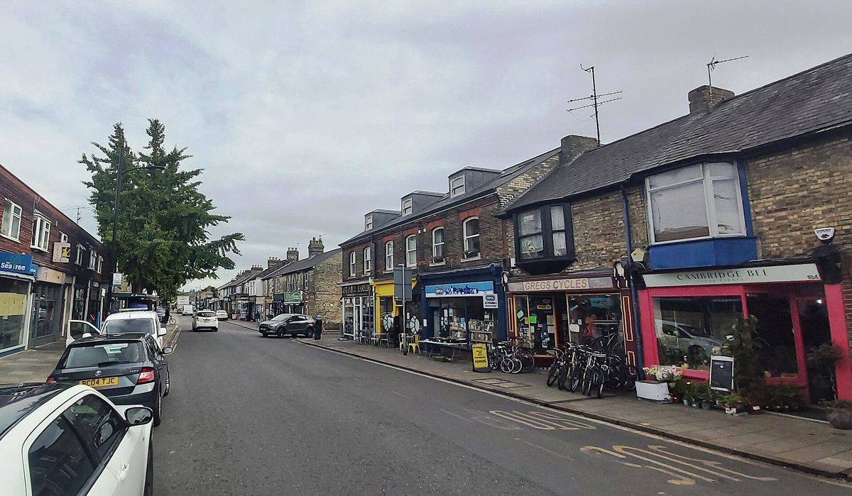 A row of small independent shops with colourful fronts along Mill Road
