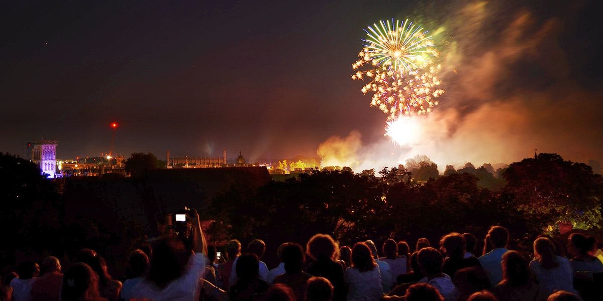 Fireworks bursting over the River Cam and college buildings at night
